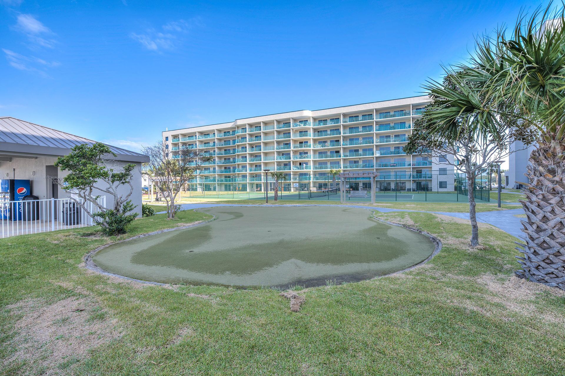 A hotel with a large building, a swimming pool, and a tennis court.