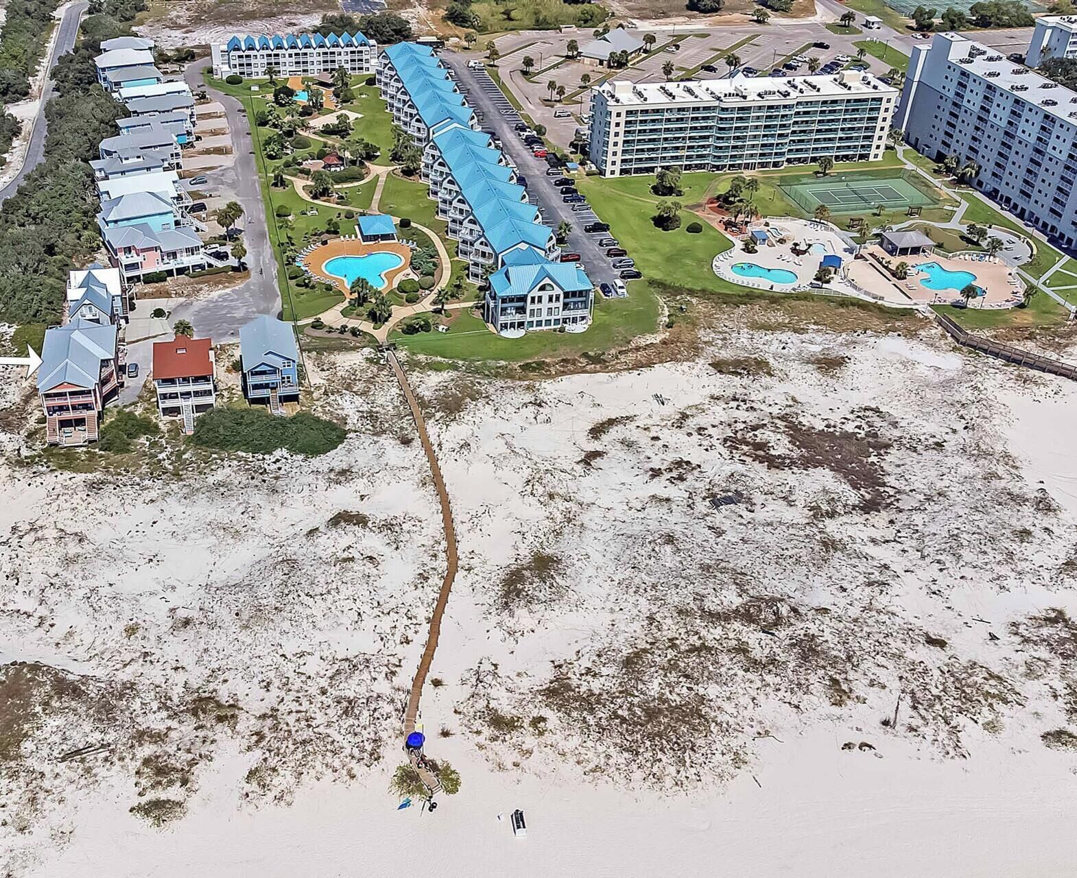 A resort with multiple buildings, a central pool, and a beach area.