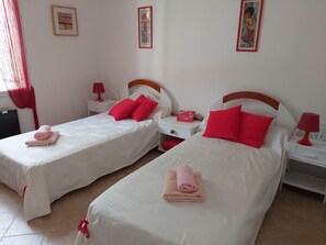 A hotel room with two beds, each with white bedding and red pillows. There are two bedside tables with lamps and a small red bag on one. - BEAUTIFUL RECENT PROPERTY WITH ALL COMFORT, 5 MINS FROM VANS (Pigère)