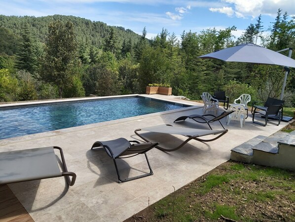 A swimming pool with lounge chairs and an umbrella, surrounded by a forested hillside. - BEAUTIFUL RECENT PROPERTY WITH ALL COMFORT, 5 MINS FROM VANS (Pigère)