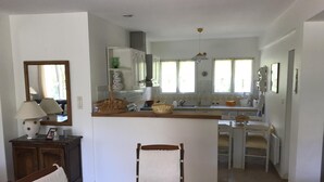 A modern kitchen with a central island, a dining area with a round table and chairs, and a large mirror on the wall. - BEAUTIFUL RECENT PROPERTY WITH ALL COMFORT, 5 MINS FROM VANS (Pigère)