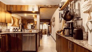 A modern kitchen with wooden cabinets, a central island, stainless steel appliances, and a hanging pot rack. - Casa del Ojo - 3 King beds - Heated Pool - BBQ - 1 mile to downtown FTL (Fort Lauderdale)