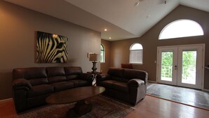 Ein geräumiges Wohnzimmer mit einer großen braunen Ledersitzgruppe, einem Couchtisch und einem Wandbild mit Zebra-Muster.