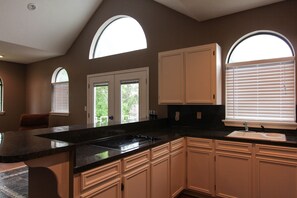 A kitchen with a large island, white cabinets, and a window with blinds. - On The Water Get-A-Way, Rayburn Country (Brookeland)