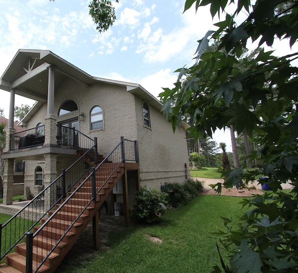 A two-story house with a covered porch, a staircase, and a well-maintained lawn. - On The Water Get-A-Way, Rayburn Country (Brookeland)