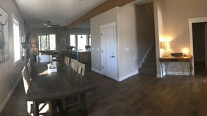 A spacious dining area with a large wooden table and chairs, a kitchen in the background, and a staircase leading to another level. - Look No Further! Brand New Build in Winter Park/Fraser (Fraser)