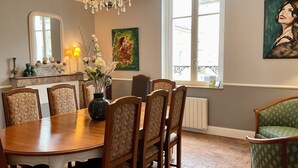 Un comedor con una mesa y sillas de madera, una araña y obras de arte en las paredes.