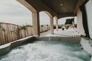 Un espace avec un jacuzzi, entouré d’une clôture en bois et agrémenté de plantes en pot.