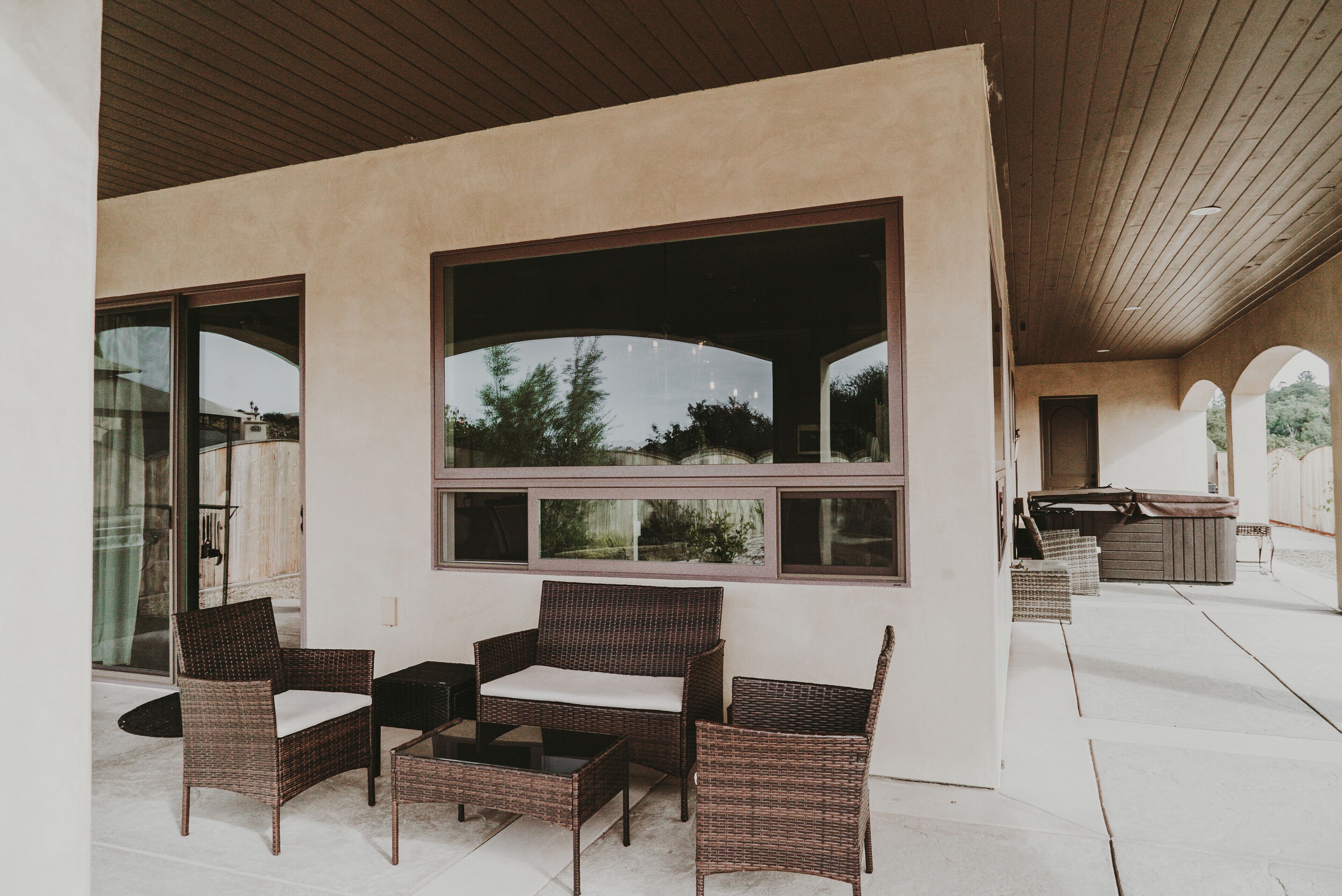 An outdoor seating area with wicker furniture and large windows.