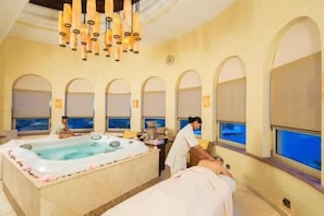 Une salle de spa dotée d’une grande baignoire, de fenêtres en arc de cercle et d’un lustre au plafond.