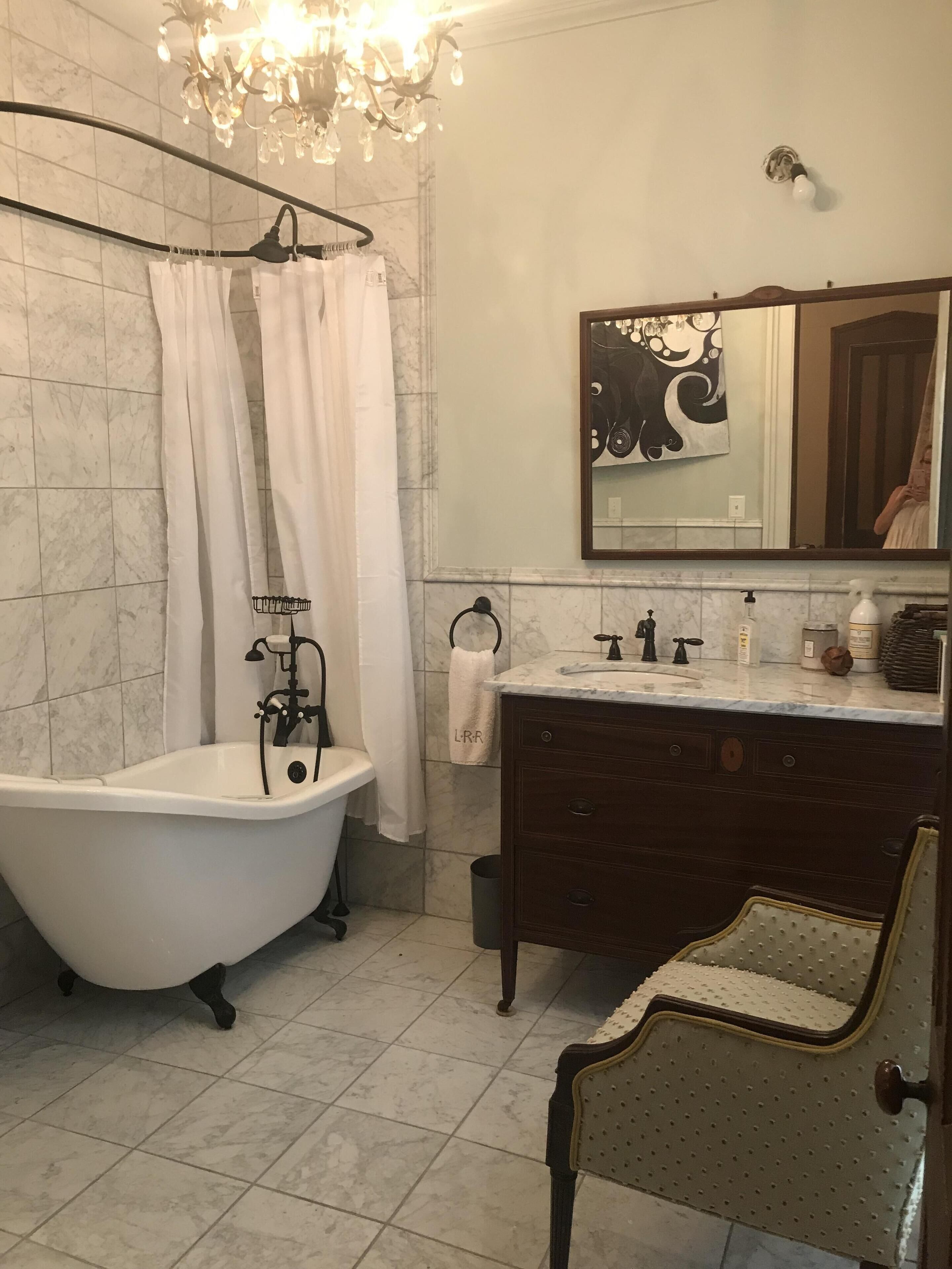 Ein Badezimmer mit freistehender Badewanne, einem Schminktisch mit Spiegel und einem Kronleuchter.