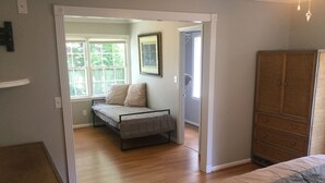 A bedroom with a bed, a dresser, and a window with a view of trees.
