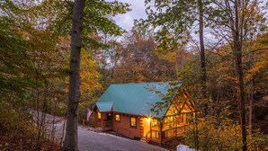 A rustic cabin with a green roof, surrounded by autumn foliage. - Cardinal Cabin (Hocking Hills area) (Sugar Grove)