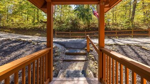 A wooden covered walkway leading to a parking area surrounded by trees. - Cardinal Cabin (Hocking Hills area) (Sugar Grove)
