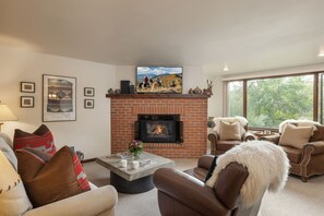 A living room with a fireplace, comfortable seating, and artwork on the walls.