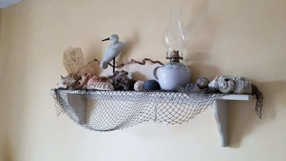 A shelf with a bird figurine, a lamp, and various shells.