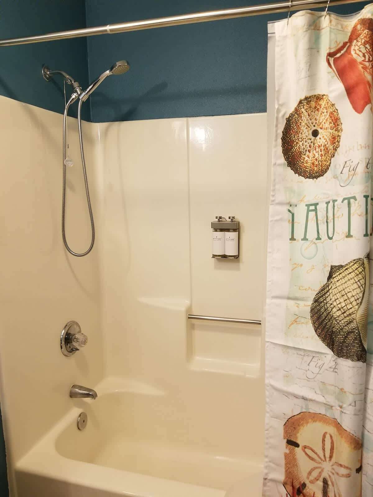 Een badkamer met een douche, een bad en een handdoekhouder.
