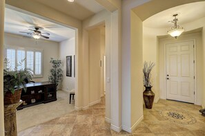 A hallway with a ceiling fan, a door, and a decorative floor pattern.