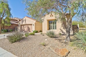 A house with a stucco exterior, a stone foundation, and a gravel driveway.