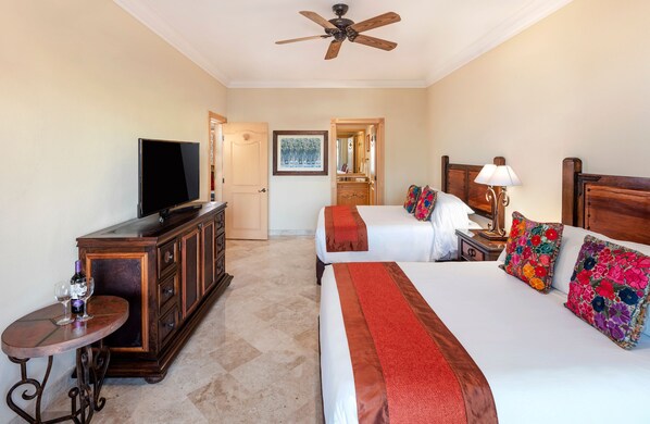 A hotel room with a bed, a TV, a dresser, and a small table with a wine bottle and glasses.