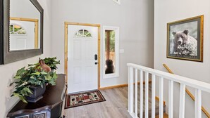 A hallway with a white door, a potted plant, a framed picture, and a staircase.
