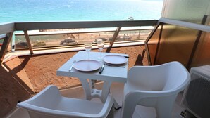 Un balcon avec une table dressée pour deux personnes, donnant sur une plage.