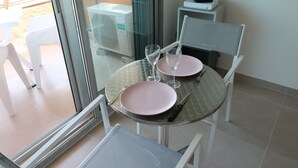 Un coin repas avec une table en verre, deux assiettes roses et des couverts.