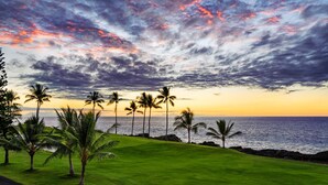 Ein Golfplatz mit Blick auf das Meer und einem Sonnenuntergangshimmel.