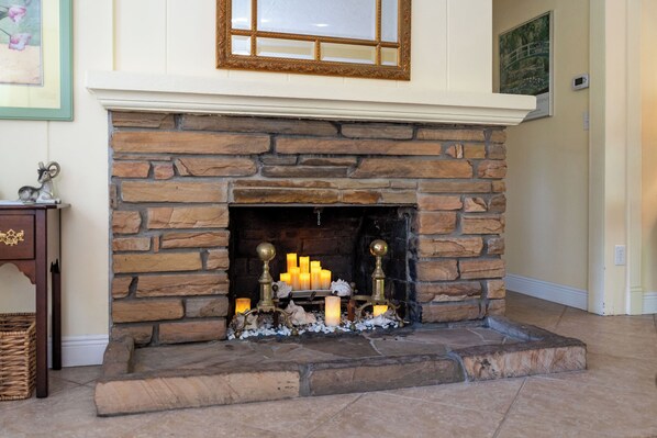 Una chimenea de piedra con velas encendidas y objetos decorativos.