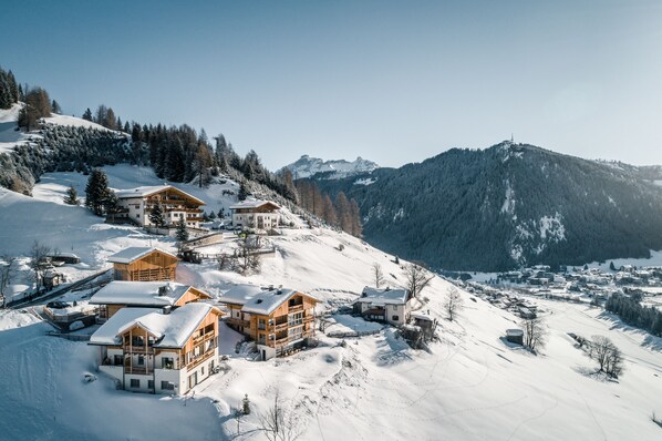 A snow-covered mountain village with wooden chalets and a ski resort. - Lüch de Costa (Corvara in Badia)