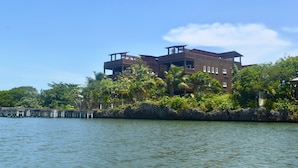 A multi-story hotel with a waterfront view, featuring balconies and a stone facade. - Luxury 3 Bedroom/2 Bath Waterfront Condo in a quiet part of West End, Roatán (West End)