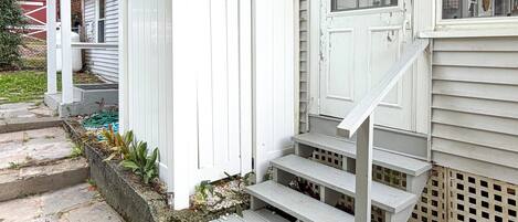 Eine weiße Holztreppe führt zu einer Veranda mit einem weißen Zaun.