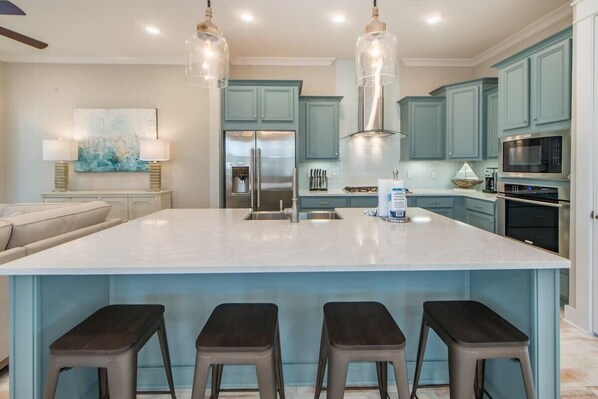 A modern kitchen with a large island, stainless steel appliances, and light blue cabinetry.