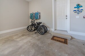 A room with a bicycle leaning against the wall, a door with a decorative anchor, and a patterned doormat.