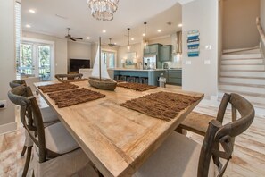 A spacious dining area with a large wooden table, several chairs, and a decorative sailboat centerpiece.