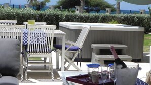 An outdoor seating area with white furniture, a hot tub, and a view of the sea.