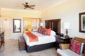 A hotel room with a large bed, a wooden nightstand, a desk, a chair, a wardrobe, a ceiling fan, and a bathroom visible through an open door. - 2BR at Estancia on Medano Beach! (Cabo San Lucas)