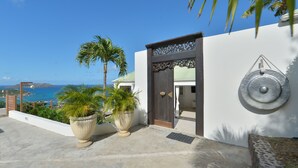 Un edificio moderno con vistas al mar, que presenta una planta grande en maceta y un elemento decorativo en la pared.