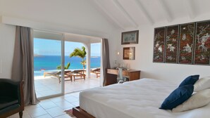 Un dormitorio con una cama grande, un escritorio y vista al océano.
