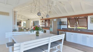 Una cocina amplia con armarios blancos, encimera de madera y una lámpara colgante.