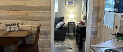 A compact kitchen with a stove, a dining area with a table and chairs, and a cozy living space with a couch and a lamp.