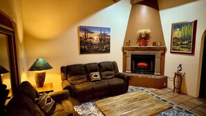 A cozy living room with a fireplace, leather sofas, a patterned rug, and wall art.