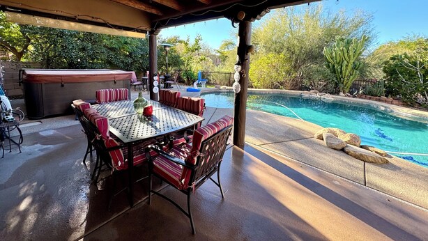 An outdoor patio with a pool, covered seating, and a barbecue area.
