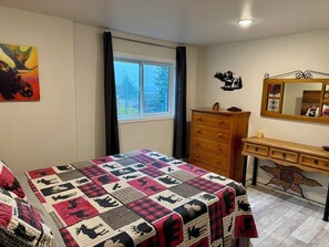A bedroom with a bed, a dresser, a mirror, and a window.