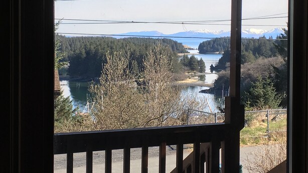 Une vue depuis un balcon donnant sur un lac, entouré d’arbres et de montagnes.
