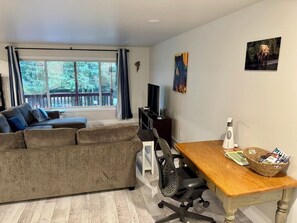 A living room with a sofa, a wooden table, a TV, and a window with curtains.