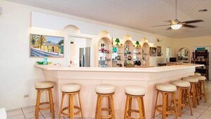 Een keuken met een centraal eiland, barstoelen en een plafondventilator.