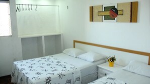 Une chambre d’hôtel avec deux lits simples, une petite table de chevet ornée d’un vase de fleurs et une œuvre d’art accrochée au mur.