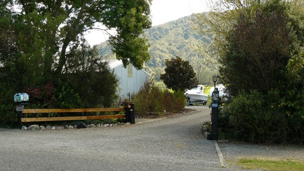 A gravel driveway leading to a building with a boat trailer in the background. - Cosy, self contained boutique studio. (Linkwater)