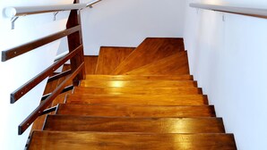 A wooden staircase with white walls and two wall-mounted lights.